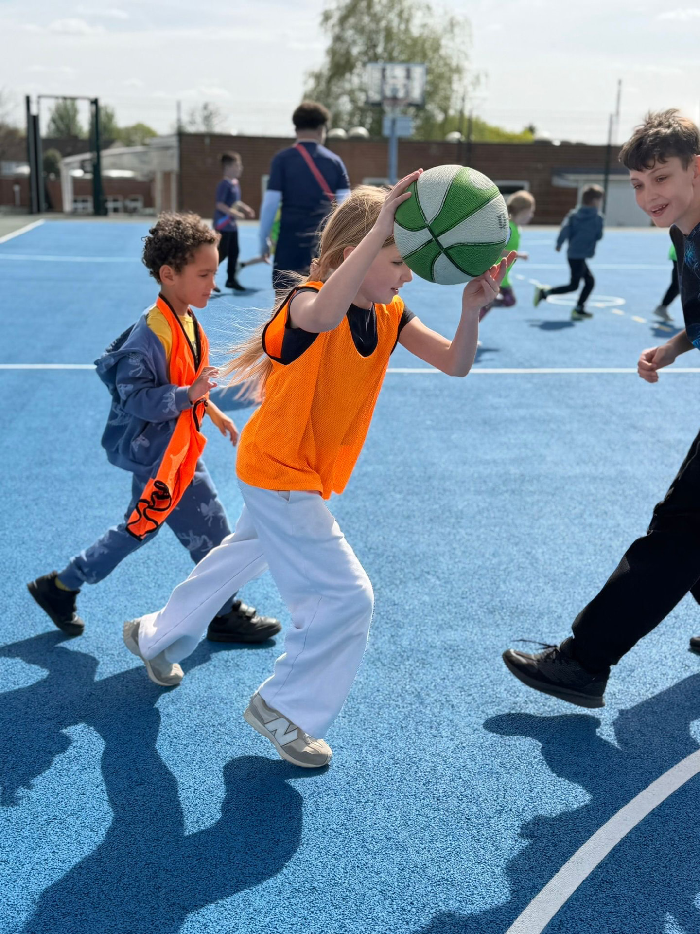 Foundation coach with two children during an after-school sports club in a school hall