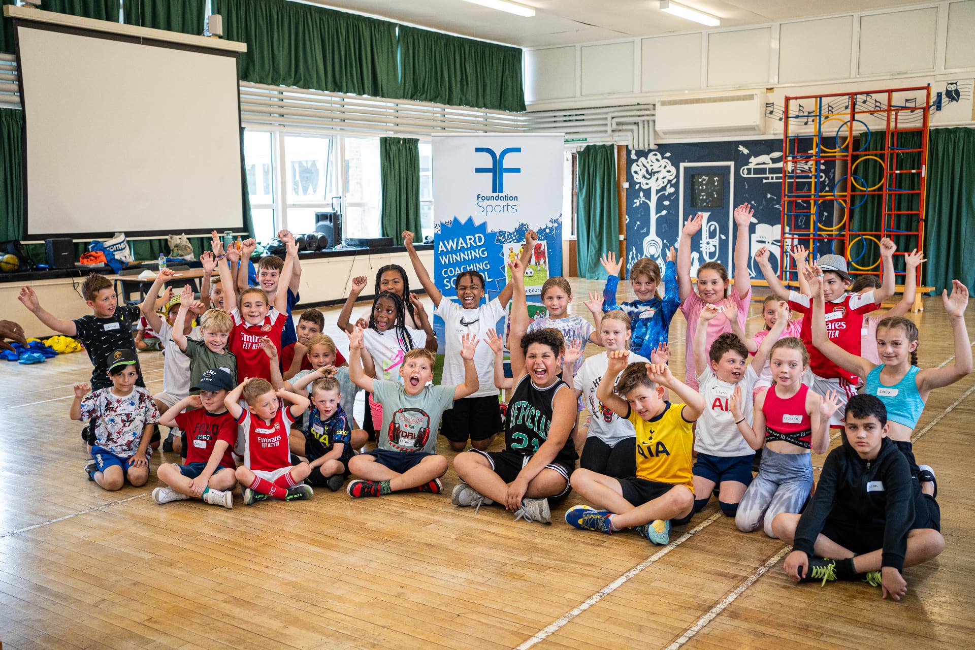 Large group of children cheering with hands raised at a Foundation holiday camp