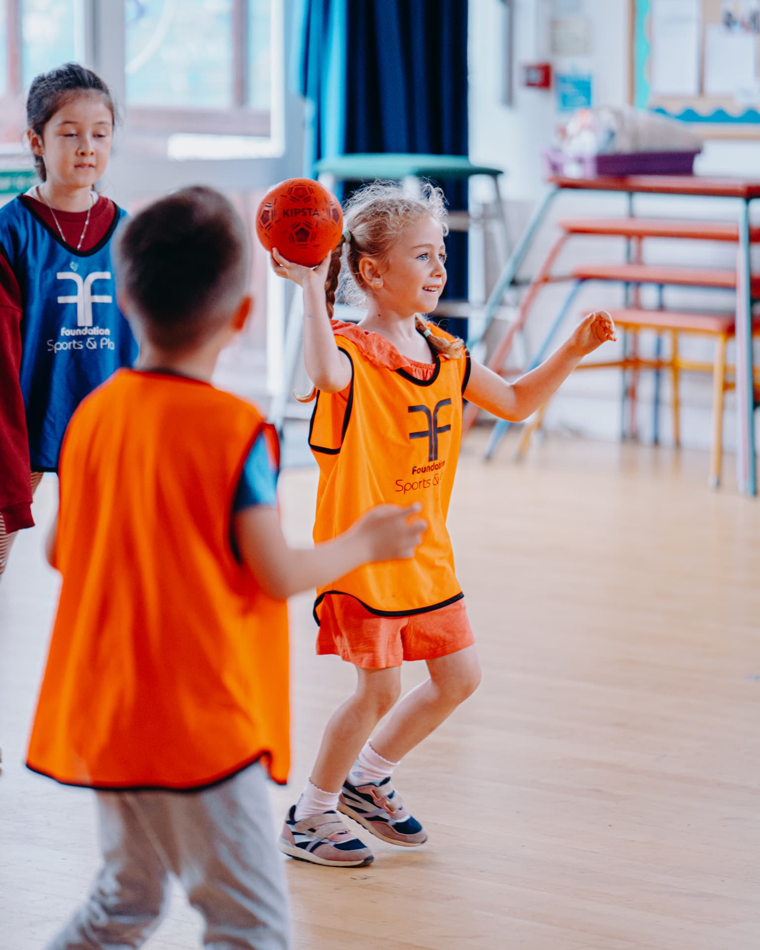 Children enjoying a Foundation ball game in a school hall